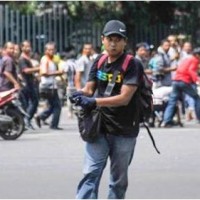 Foto ini dirilis oleh agensi berita China Xinhua, seorang pria tak dikenal dengan senjata berjalan dengan latar belakang kerumunan orang, di kawasan Jalan MH Thamrin, dekat pusat perbelanjaan Sarinah, Jakarta, 14 Januari 2016.